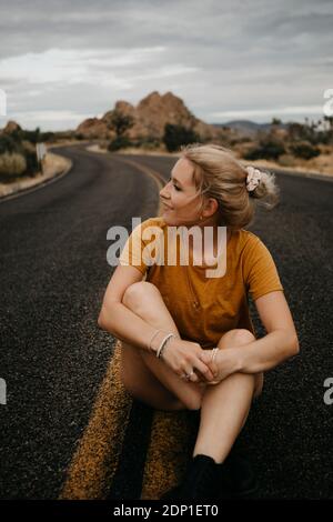 Woman sitting on road, Joshua Tree National Park, California, USA Stock Photo