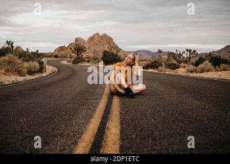 Woman sitting on road, Joshua Tree National Park, California, USA Stock Photo