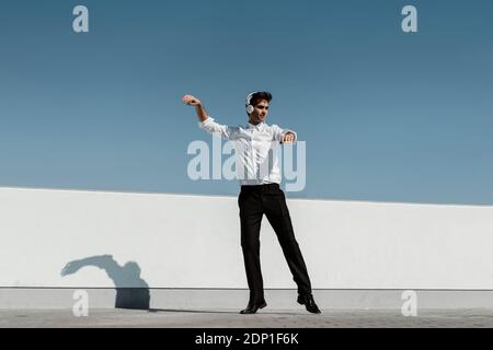 Ballet dancer with headphones practising on roof terrace Stock Photo