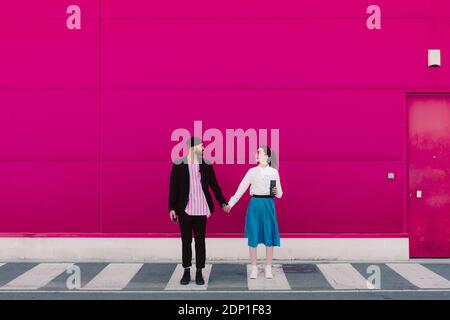 Couple standing on crosswalk, face to face and holding hands Stock Photo