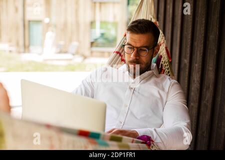 Man on hammock using laptop Stock Photo