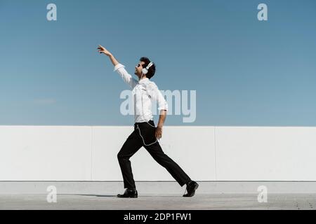 Ballet dancer with headphones practising on roof terrace Stock Photo
