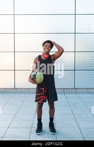 Portrait of a smiling young man with headphones holding basketball Stock Photo