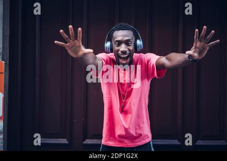Portrait of excited man wearing pink t-shirt listening to music with headphones Stock Photo
