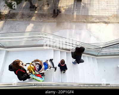 People with children descending the steps of a pedestrian flyover in Alimos, Greece Stock Photo