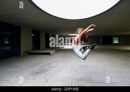 Sporty young woman jumping in courtyard Stock Photo