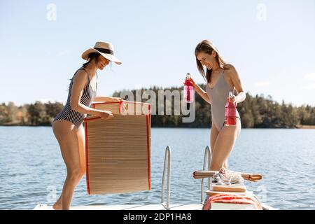 Female friends relaxing on jetty Stock Photo