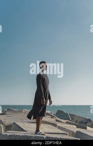 Young man standing at the coast wearing black kaftan Stock Photo