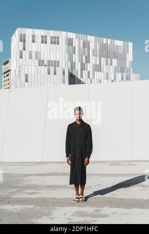 Young man wearing black kaftan standing outdoors Stock Photo