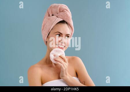 Nice happy girl wearing towels posing with cosmetic sponge isolated over blue background Stock Photo