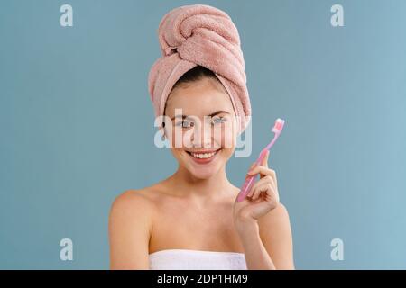 Nice happy girl wearing towels posing with toothbrush isolated over blue background Stock Photo
