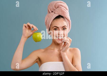 Nice happy girl wearing towels smiling and posing with apple isolated over blue background Stock Photo
