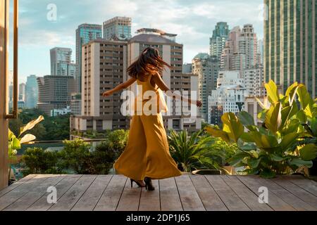 Back view of woman dancing on roof terrace, Bangkok, Thailand Stock Photo
