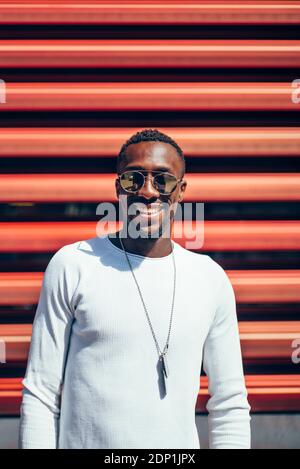 Portrait of smiling young man standing at a red wall Stock Photo