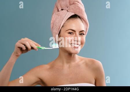 Nice happy girl wearing towels holding toothbrush with toothpaste isolated over blue background Stock Photo