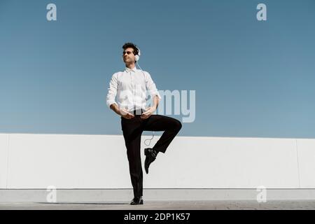 Ballet dancer with headphones practising on roof terrace Stock Photo