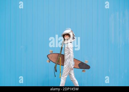 Kid dressed as an astronaut with longboard Stock Photo