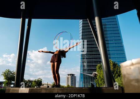 Sporty woman balancing plastic hoops on chest in modern city Stock Photo