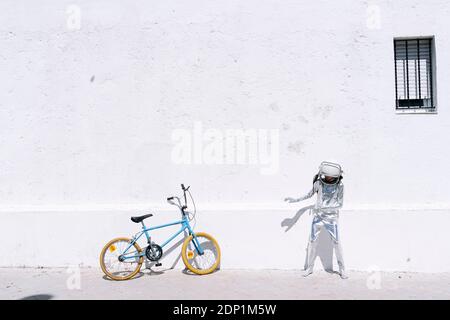 Boy in astronaut costume standing by bicycle on sidewalk in city Stock Photo
