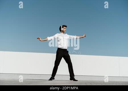 Ballet dancer with headphones practising on roof terrace Stock Photo