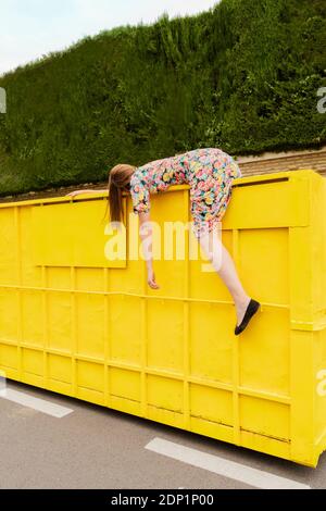 Exhausted woman hanging over edge of yellow container Stock Photo - Alamy