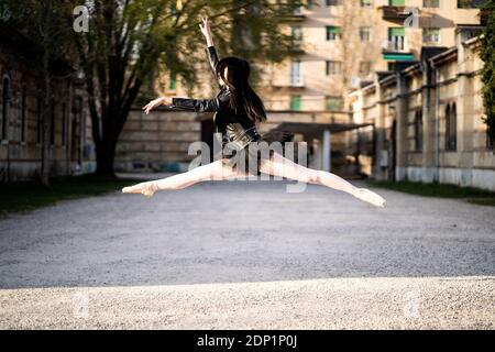 Italy, Verona, Ballerina wearing leather jacket and tutu jumping midair Stock Photo