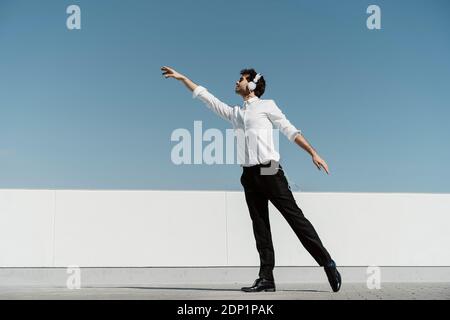 Ballet dancer with headphones practising on roof terrace Stock Photo
