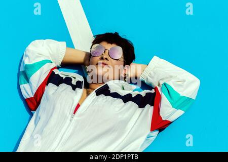 Portrait of woman wearing sunglasses and lying on ground Stock Photo