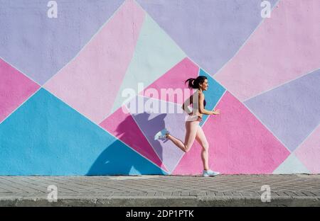Mature woman running in front of a colorful wall Stock Photo