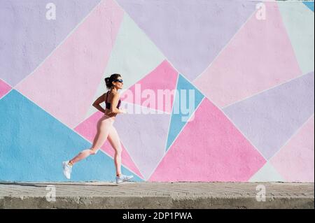 Mature woman running in front of a colorful wall Stock Photo