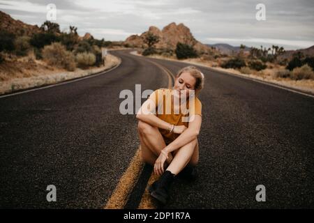 Woman sitting on road, Joshua Tree National Park, California, USA Stock Photo