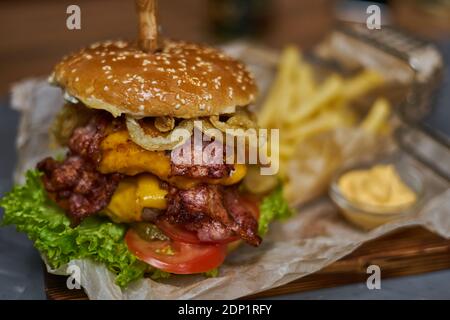 delicious burger with double cutlet and French fries on a wooden board Stock Photo