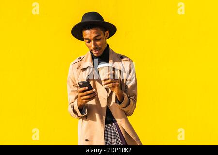 Young man with coffee cup, using smartphone Stock Photo