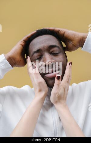 Portrait of relaxed young man  touched by woman's hands Stock Photo