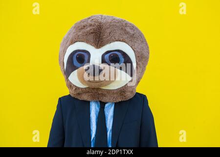 Portrait of businessman with meerkat mask in front of yellow wall Stock Photo