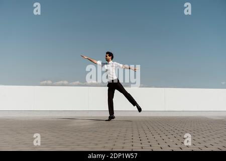 Ballet dancer with headphones practising on roof terrace Stock Photo