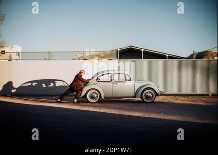 Senior man pushing vintage car Stock Photo