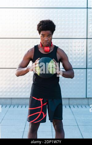 Spain, Madrid, Young athletic Afro man trainig with basketball ball in the city, Youth, Ethnicity, Connection, Sport Stock Photo