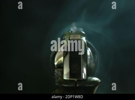 revolver gun with smoke floating in the air after shoot on black background Stock Photo