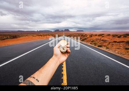 USA, Utah, Hand holding compass over road to Monument Valley Stock Photo