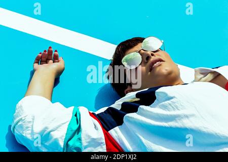 Portrait of woman wearing mirrored sunglasses and lying on ground Stock Photo