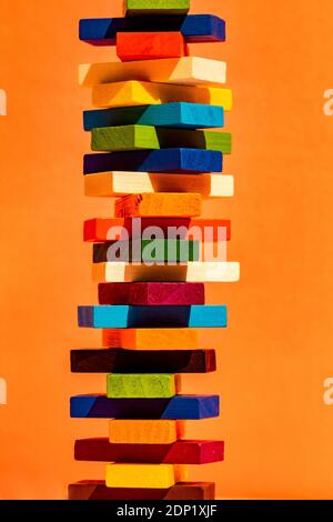 Colorful toy blocks stack against orange background Stock Photo