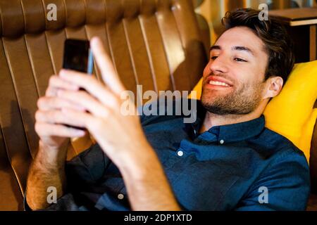 Man lying on couch using cell phone Stock Photo