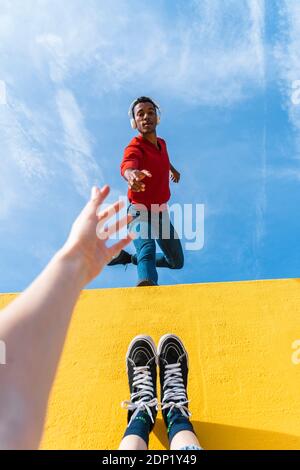 Young man with headphones, dancing for person, leaning on yellow wall Stock Photo