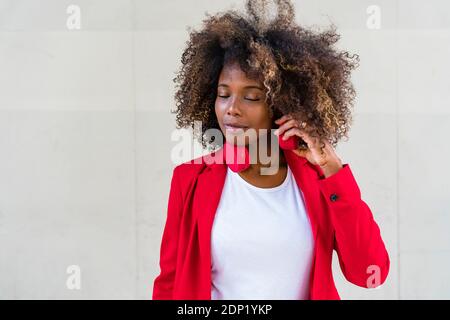 Contemplating woman with headphones around neck standing against wall Stock Photo