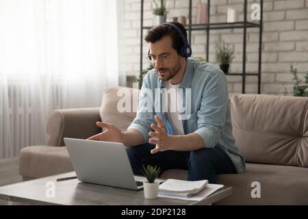 Young man teacher giving distant lesson in headset using pc Stock Photo