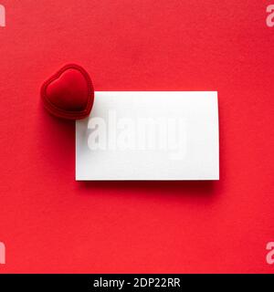 Blank white letter message mockup and engagement ring in box on red background. Stock Photo