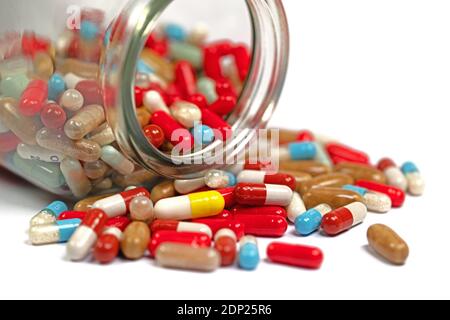 Lots of colorful pills, capsules, medicine, in glass against white background Stock Photo