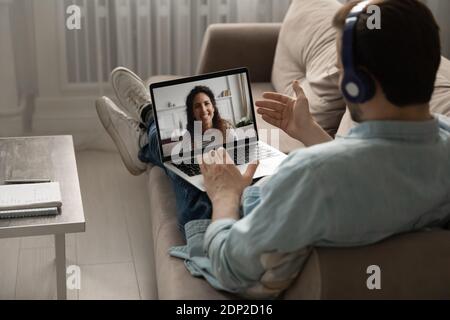Calm millennial man relaxing on sofa chatting with wife online Stock Photo