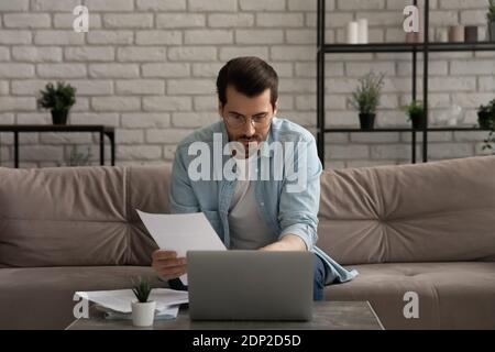 Serious thoughtful young man working with documents at home office Stock Photo